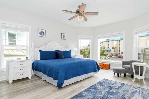 A bedroom with a large bed, a ceiling fan, and a view of the outside. - Coastal Home w/Private Pool & Volleyball Court! 🏐💦🌺 (Miramar Beach)