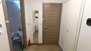Un couloir avec une porte en bois, un mur blanc et une petite table entourée de chaises.