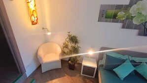 Une chambre à coucher moderne avec un lit, une chaise, une petite table et une plante en pot.