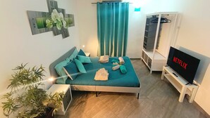 Une chambre à coucher moderne avec un lit, une télévision, une armoire et une plante en pot.