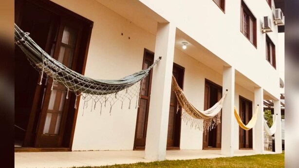 A building with multiple balconies, each with a hammock hanging.