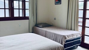 A room with two beds, a window, an air conditioning unit, and a picture on the wall.