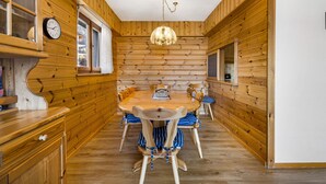 A wooden interior with a round dining table, chairs, a chandelier, and a clock on the wall. - Christiania I F2 - 4 pers - près des pistes (Haute-Nendaz)
