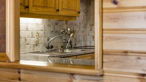 A kitchen with wooden cabinets, a tiled backsplash, and a stainless steel sink. - Christiania I F2 - 4 pers - près des pistes (Haute-Nendaz)