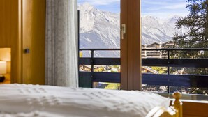 A bedroom with a bed, a window with a mountain view, and a wooden railing. - Christiania I F2 - 4 pers - près des pistes (Haute-Nendaz)
