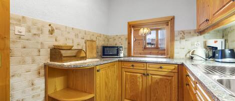 A kitchen with wooden cabinets, a microwave, a toaster, and a sink.