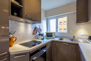 A modern kitchen with a built-in oven, microwave, and stainless steel sink.