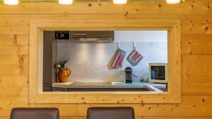 Une cuisine avec un lambris en bois, une hotte de cuisine en acier inoxydable, un four à micro-ondes et des ustensiles de cuisine suspendus.