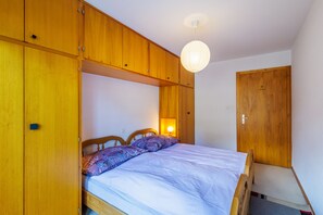 Une chambre à coucher avec un lit, une armoire en bois et un luminaire suspendu.