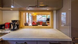 Une cuisine moderne dotée d’un coin repas intégré, d’une machine à café et offrant une vue sur l’extérieur.