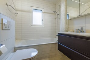 Une salle de bain avec une baignoire, des toilettes et un meuble-lavabo avec un miroir.