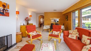 Un salon chaleureux avec une cheminée, des meubles en bois et un coin repas comprenant une table et des chaises.