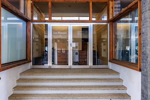 A staircase leading to a building entrance with glass doors and wooden framing.