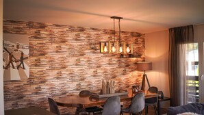 Un espace repas moderne avec un mur en bois, un lustre et une table à manger avec des chaises.