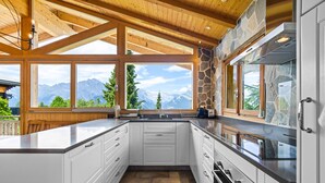 A modern kitchen with white cabinets, a large island, and a stone accent wall.