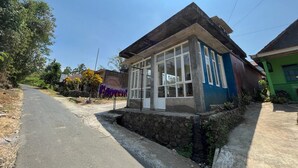 A small, single-story house with a large window and a porch. - OYO Life  92982 Kost Berkah Ibu (Singasari)