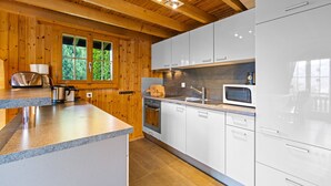 A modern kitchen with wooden walls, white cabinets, and a granite countertop. - Darjean - 8 pers - belle vue (Haute-Nendaz)