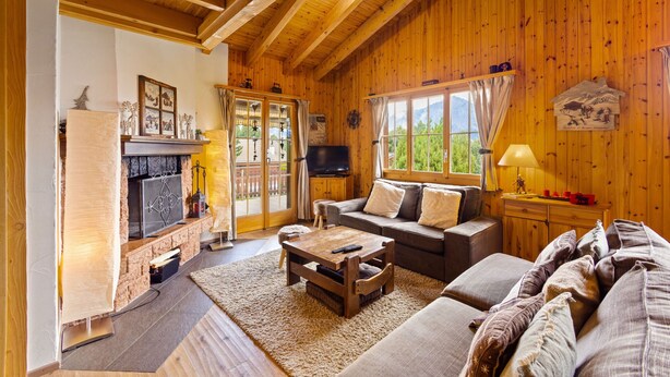 A cozy cabin interior with a fireplace, wooden walls, a sofa, and a television. - Darjean - 8 pers - belle vue (Haute-Nendaz)