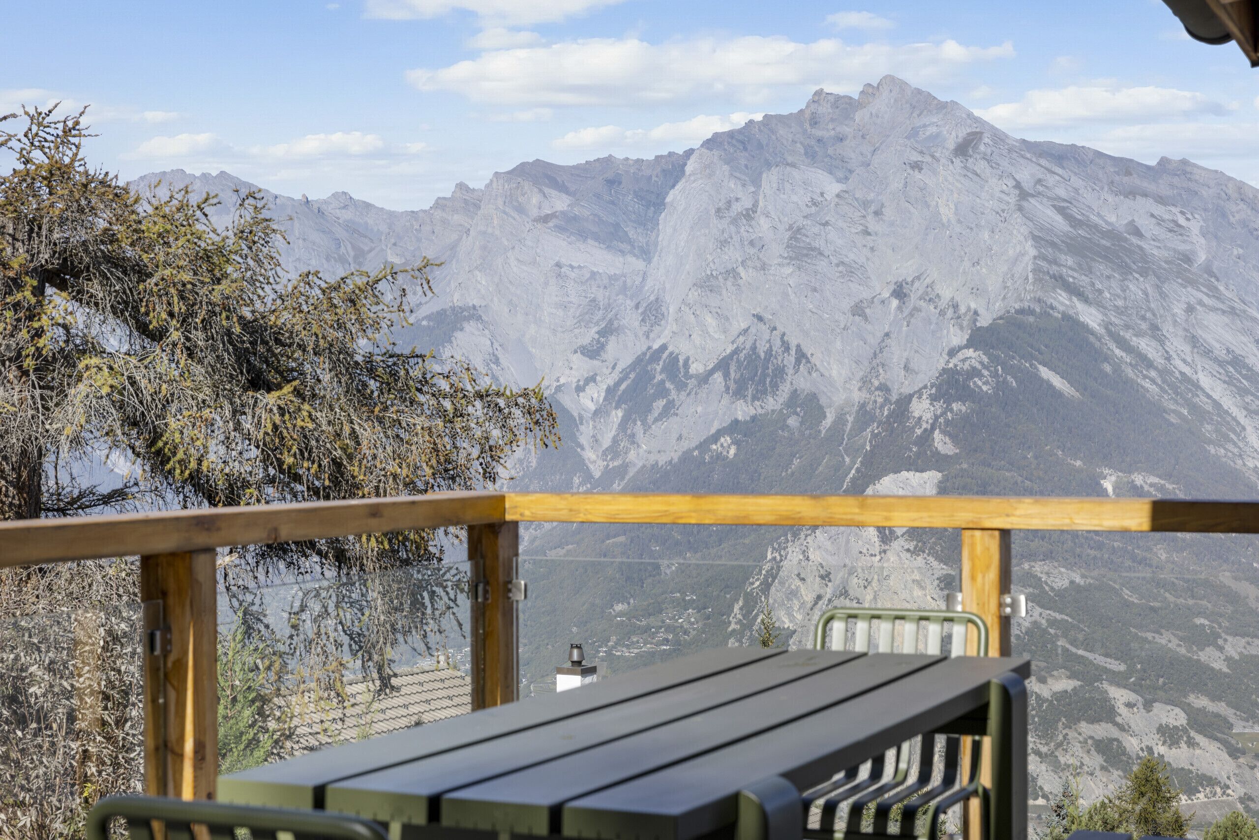 Una terraza de madera con un banco que da a un paisaje montañoso.