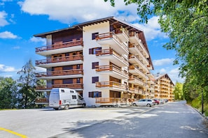 A multi-story hotel with balconies, a parking area, and a van parked in front.