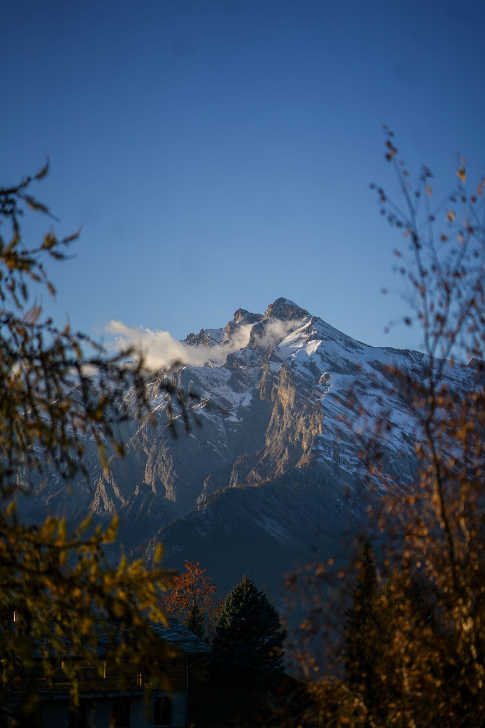 A mountain with snow-covered peaks and a clear sky.