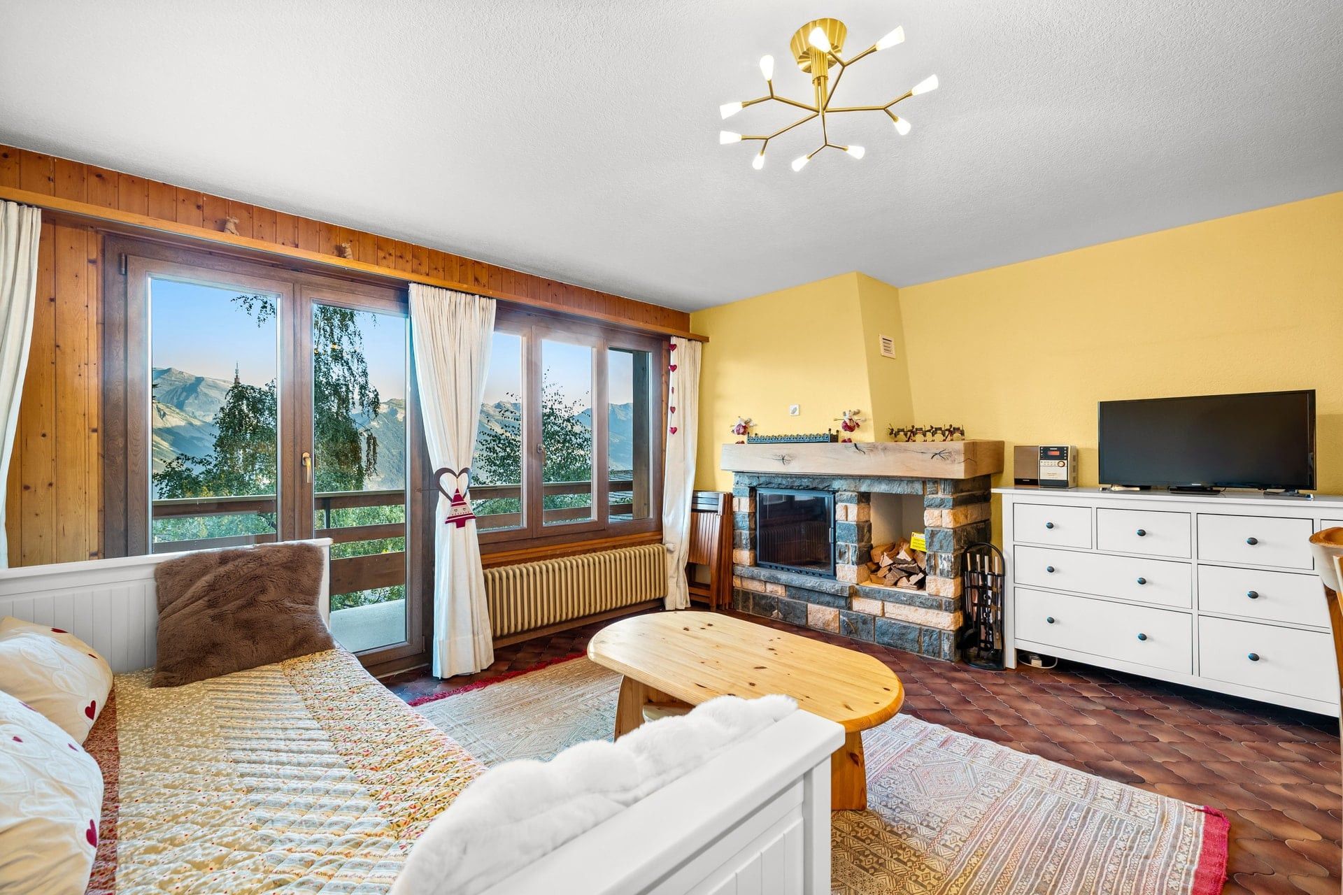 A cozy room with a fireplace, a television, and a large window with a mountain view.