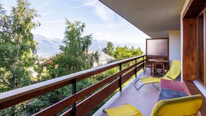A balcony with a view of mountains, a table, and yellow chairs. - Quille du Diable 35 - 4 pers - piscine (Haute-Nendaz)
