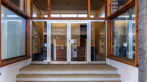 A staircase leading to a building entrance with glass doors and wooden framing. - Les Platanes E4 - 5 pers - centre station (Haute-Nendaz)