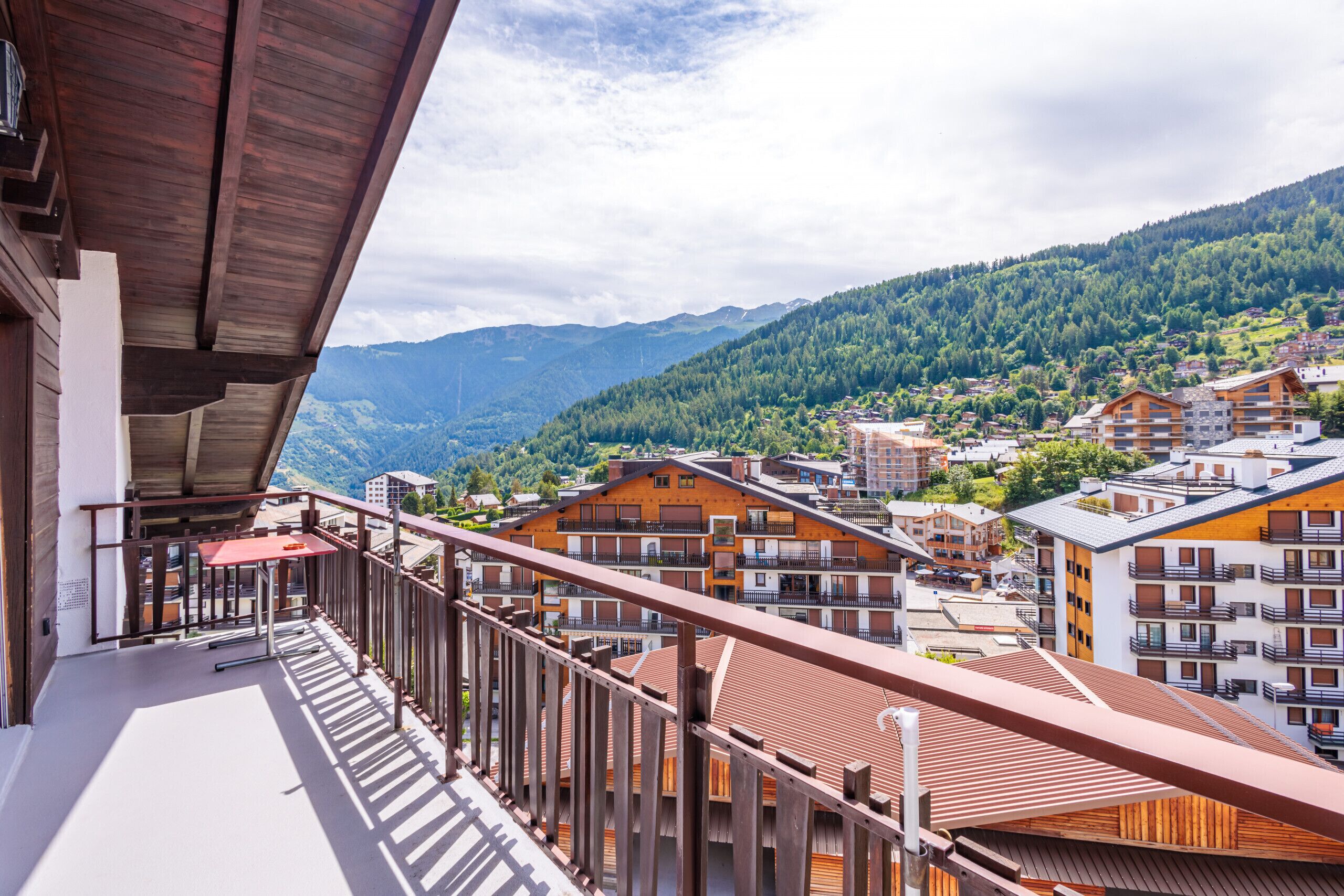 A balcony with a view of a mountainous landscape and a town below.