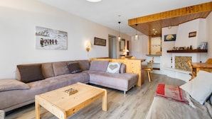 A living room with a sofa, a wooden coffee table, and a red and white throw blanket.