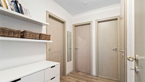 A hallway with a white dresser, wicker baskets, and two wooden doors.