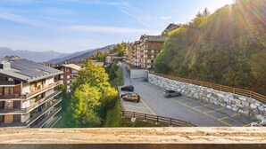 A multi-story hotel with a parking area, surrounded by mountains and greenery.