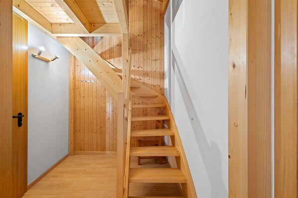 Una escalera de madera con una pared blanca a un lado y una puerta de madera al otro.
