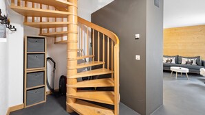 Un intérieur moderne avec un escalier en colimaçon en bois, un canapé gris et une table basse blanche.