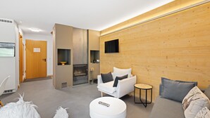 Un salon moderne avec une cheminée, un canapé, une table basse ronde et un téléviseur fixé au mur.