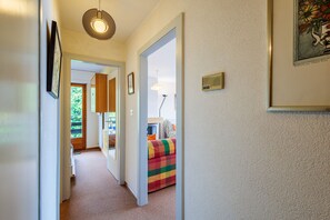 A hallway with a door leading to a room with a colorful bed.