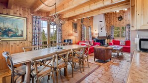 A wooden cabin interior with a dining table, chairs, a sofa, and a fireplace. - Gisèle - 8 pers - près des pistes (Haute-Nendaz)