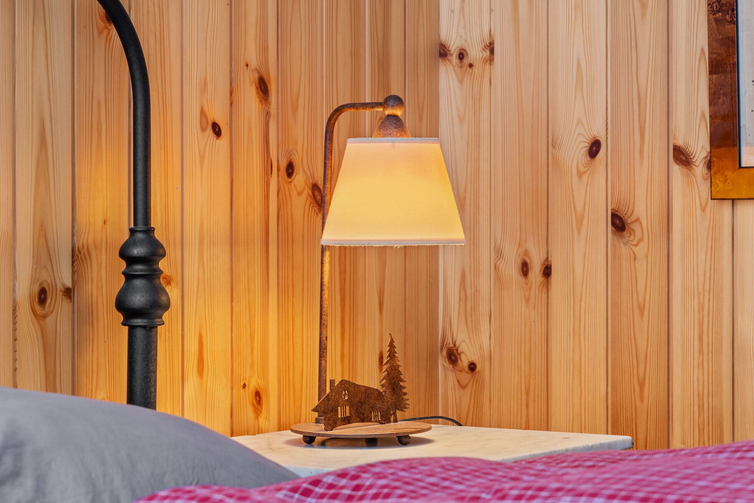 Un mur en bois, avec une lampe et une petite maquette de maison en bois posée sur une table.