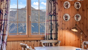 A wooden interior with a large window, wooden walls, a table, chairs, and a lamp. - Gisèle - 8 pers - près des pistes (Haute-Nendaz)