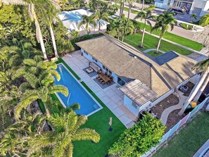 A residential property with a swimming pool, patio furniture, and lush greenery.