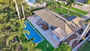 An aerial view of a house with a swimming pool, patio furniture, and a well-maintained lawn. - Pet-Friendly Inland Home | Resort Style Yard & Pool (Marco Island)