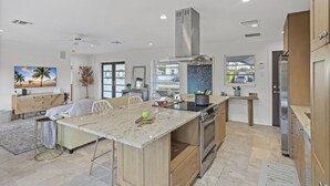 A modern kitchen with a large island, built-in oven, and stainless steel appliances. - Pet-Friendly Inland Home | Resort Style Yard & Pool (Marco Island)