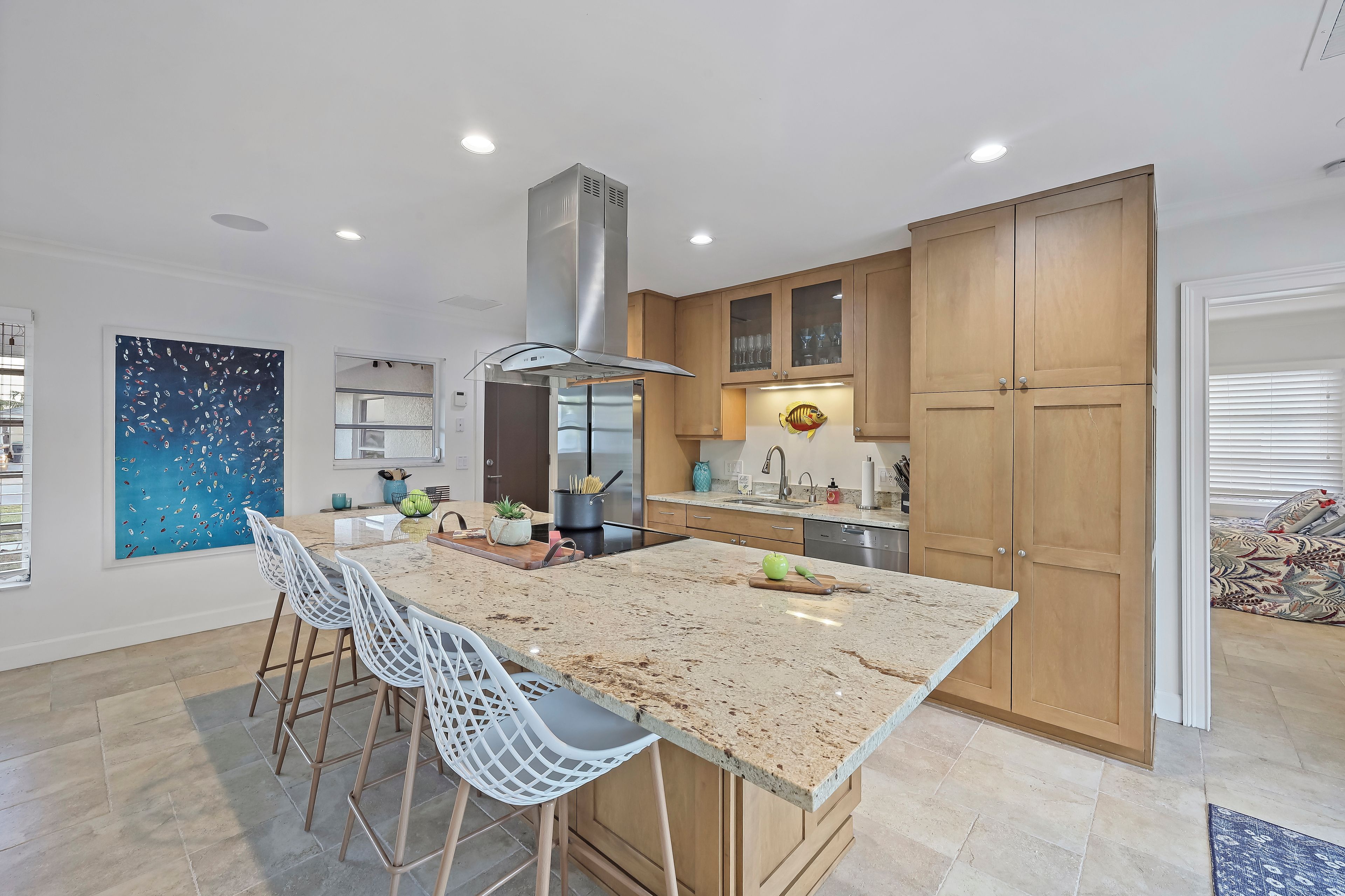 Una cocina moderna con una isla grande, taburetes de bar y armarios de madera.