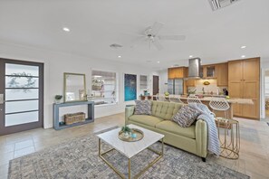 A modern living room with a sofa, coffee table, and a view of the kitchen. - Pet-Friendly Inland Home | Resort Style Yard & Pool (Marco Island)