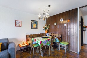 Zona pranzo con una panca in legno, un tavolo con tovaglia a fiori e un lampadario.