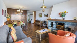 Una sala de estar con sofá, sillón, mesa de centro, chimenea y paredes de madera.