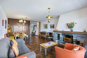 Ein Wohnzimmer mit Sofa, Sessel, Couchtisch, Kamin und Holzwänden.