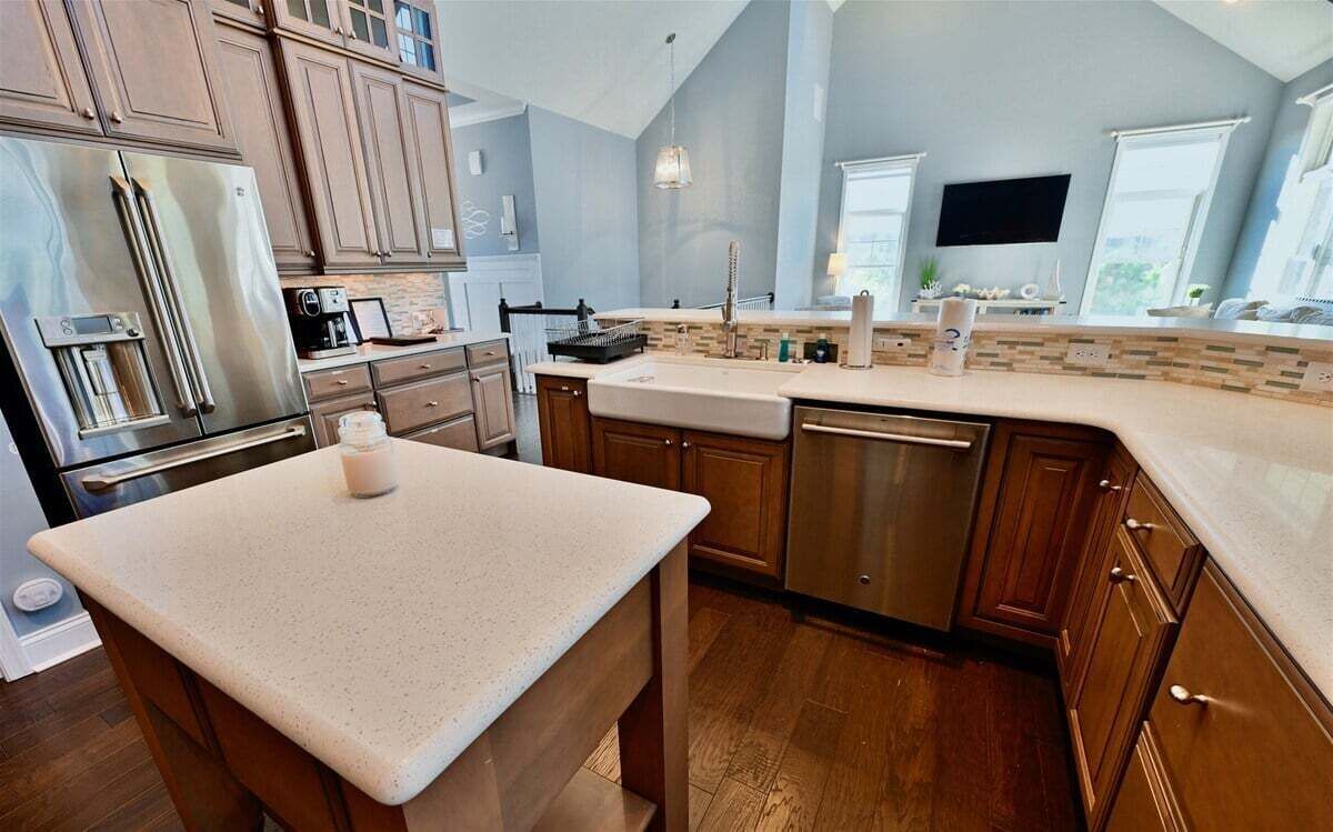 A kitchen with wooden cabinets, stainless steel appliances, a large island, and a window overlooking the outdoors.