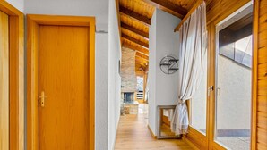 A hallway with wooden flooring, a wooden door, and a window with curtains. - Les Hauts-de-Nendaz A C5 - 5 pers - ski In&Out (Haute-Nendaz)