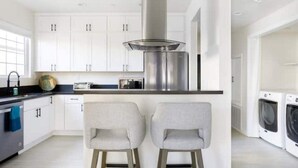 A modern kitchen with white cabinets, a stainless steel range hood, and two bar stools. - NoHo Toluca Lake Luxury Near Universal Studios  (Los Angeles)